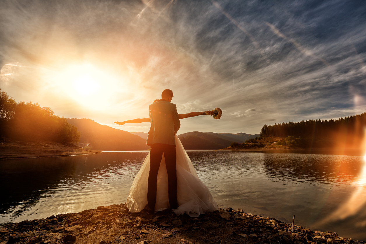 nride and groom embracing at sunset, loving and feeling happy.photo taken at sunset, bride is holding her arms raised.